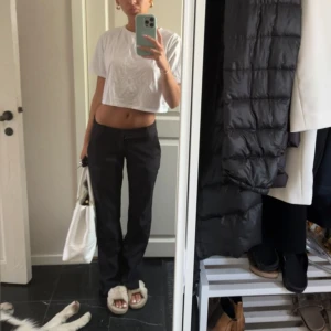 Svarta kostymbyxor - Säljer ett par svarta kostym byxor med låg midja och raka ben. Byxorna har en klassisk look med enkel knäppning framtill och är perfekta för en clean och stilren outfit. Materialet känns mjukt och följsamt, passar till allt.