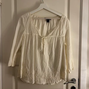 Vit blus från Ellos - Säljer en söt vit blus från Ellos med trekvartsärmar och knytning framtill. Perfekt för en avslappnad stil. Blusen har en luftig passform och är gjord i ett lätt material.