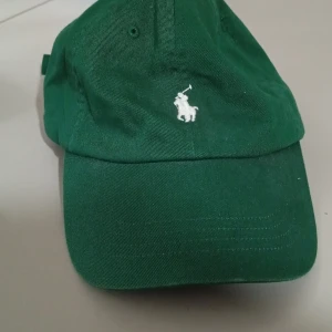 Grön Polo Ralph Lauren keps med broderad logga - Snygg grön keps med en vit broderad logga framtill. Perfekt för en avslappnad stil och skydd mot solen.