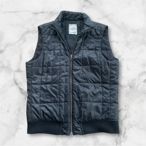 J.Lindeberg väst - Stilren, snygg svart quiltad väst från J.Lindeberg med dragkedja framtill. Storlek M men passar även en större S. Priset är inte slagit i sten. Skriv om du har några frågor kring produkten!