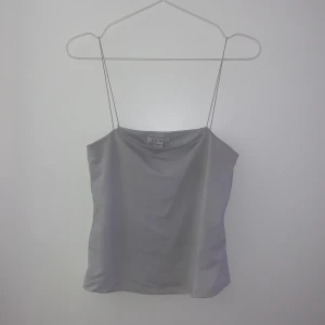 Vit linnetopp från New Yorker - Säljer en stilren vit linnetopp från New Yorker. Toppen har tunna axelband och en enkel design som passar perfekt till både vardag och fest. Materialet är mjukt och bekvämt.