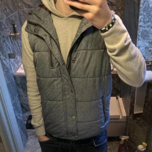 Väst med luva - Snygg grå quiltad dunväst med luva perfekt inför våren. Västen är i Str S men passar även M. Tveka inte på att kontakta mig vid minsta fundering🙌