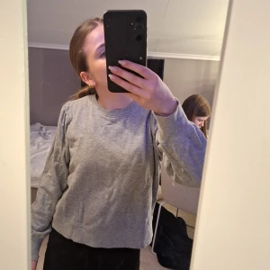 Grå tröja från KappAhl - Säljer en stilren grå tröja från KappAhl. Tröjan har långa ärmar och en rund halsring. Passar bra till jeans eller kjol. 