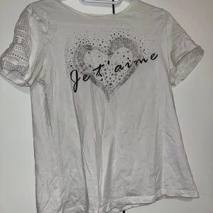 T-paita - Valkoinen t-paita, jossa edessä timantteja ja teksti sekä hihoissa reikä yksityiskohdat. Koko S. Kaikai n 40cm, pituus n 50cm.Kissatalous Mikäli hinta ei miellytä tarjoa rohkeasti!! Katsothan myös muut ilmoitukseni!!