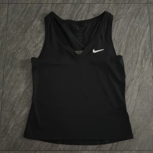 Svart linnetopp från Nike - Säljer en svart linnetopp från Nike med v-ringning. Väldigt skön och snygg🤩. Använt ca 3 gånger