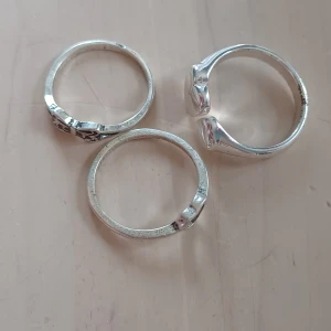 Tre silverringar med hjärtdetaljer - Säljer tre stilrena silverringar med unika hjärtdetaljer. Perfekta för att bära tillsammans eller var för sig för en elegant look. Passar utmärkt för att ge en subtil men personlig touch till din stil. Tror inte de är äkta silver 