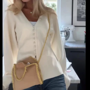 Vit kofta med knappar - Säljer en stilren vit kofta med v-ringning och knappar framtill. Perfekt för en elegant och avslappnad look. Passar bra till både jeans och kjol. 