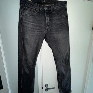Svarta jeans från Levi's - Snygga svarta jeans från Levi's av modellen 501. De har en rak passform och är perfekta för en stilren look. Jeansen har en knappgylf och är tillverkade i slitstarkt denim.