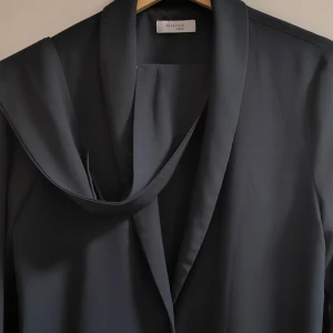 Svart kavaj från Marville Road - Elegant svart kavaj från Marville Road med långärmad design och en stilren krage. Perfekt för en sofistikerad look. Kavajen har en lös passform och är tillverkad i ett mjukt material som ger en bekväm känsla.