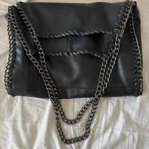 Mörkblå axelväska med kedjedetaljer - Snygg mörkblå axelväska i skinn med kedjedetaljer och flätade kanter. Väskan har en praktisk dragkedja och flera innerfack för enkel organisering. Perfekt för att ge en edgy touch till din outfit. Kedjan som är runt armen har jag gjort kortare (se sista bilden)💕💕💕