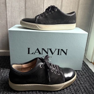 Svarta sneakers från Lanvin - Snygga svarta sneakers från Lanvin. Skorna har en stilren design med snörning och en kontrasterande vit sula. Perfekta för en stilmedveten look. Skorna är använda en del men inte så mycket. Lite slitna suler vid frågor är det bara att skriva, köpta från Care of carl och allt OG ingår 