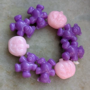 Lila och rosa armband med björnar och pumpor - Charmigt armband med lila björnar och rosa pumpor. Perfekt för att lägga till en lekfull touch till din stil. Stretchigt och lätt att bära.