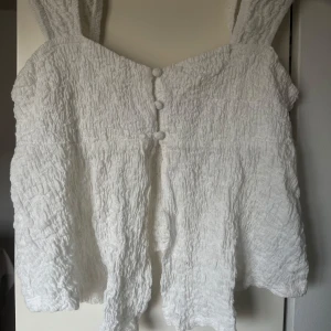 Vit topp från Gina med knappar - Säljer en vit topp ifrån Gina med små vita knappar i storlek xs-S