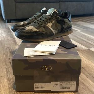 Valentino Rockrunner i camouflage - Snygga Valentino Rockrunner sneakers i ett coolt camouflage-mönster. Skorna har en klassisk snörning och är tillverkade i en mix av material för en unik look. Perfekta för att ge din outfit en edgy touch.