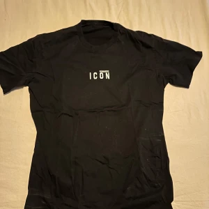 Svart t-shirt med text från Dsquared2 - Snygg svart t-shirt från Dsquared2 med texten 'ICON' tryckt på bröstet. Perfekt för en stilren och modern look. Kortärmad och tillverkad i mjukt material för extra komfort.