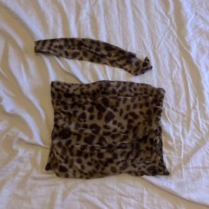 Leopardmönstrad tubtopp från Qu Style - Säljer en leopardmönstrad tubtopp från Qu Style. Toppen är ärmlös och har ett trendigt djurmönster. Perfekt för att ge en vild touch till din outfit!