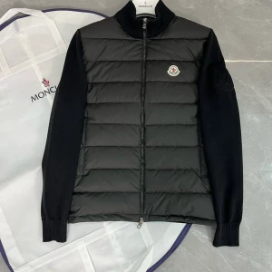 Moncler Magila Cardigan-svart-oanvänd - Moncler Maglia Cardigan – Svart – Oanvänd  Säljer en Moncler Maglia Cardigan i svart färg, helt ny och aldrig använd.  ✅ Storlek: S/M  ✅ Färg: Svart ✅ Skick: Oanvänd, 100% ny ✅ levereras med dustbag ✅ NFC-scan  Exklusiv och stilren hybridjacka med dunväst och stickade ärmar – perfekt för en lyxig och sportig look. 