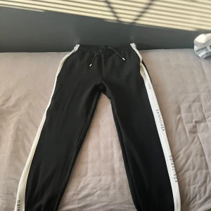 Svart träningsjacka från Balenciaga - Snygg svart träningsjacka från Balenciaga med dragkedja och vita detaljer längs ärmarna. Jackan har en hög krage och ribbade muddar. Perfekt för en stilren look.