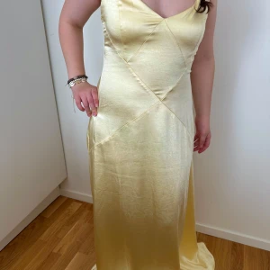 Ljus gul satin balklänning lång maxi - Elegant gul långklänning från BUBBLEROOM i ett satin. Klänningen har en v-ringad design och smala axelband. Den är figurnära. Har inte använt den en enda gång. Den är 150cm lång från axeln ner. Som referens är jag 161cm 