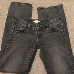 Grå jeans från Gina Tricot - Snygga grå jeans från Gina Tricot med klassisk femficksdesign och dubbla knappar i midjan. Jeansen har en stilren look med en något tvättad finish som ger dem en cool touch. Perfekta för en avslappnad stil.