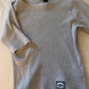 Grå ribbad topp från Ralph Lauren - Säljer en stilren grå ribbad topp från Ralph Lauren. Toppen har trekvartsärmar och en enkel design som passar perfekt till vardags. Tillverkad i 100% bomull för en mjuk och bekväm känsla. Skulle säga att den är som en S/XS!🥰