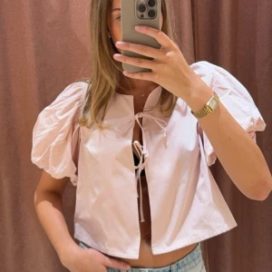 Rosa blus från Gina Tricot - Säljer en söt rosa blus från Gina Tricot med puffiga korta ärmar och knytning framtill. Perfekt för en somrig look! 💖
