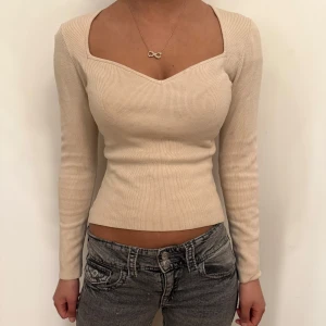 Beige ribbad topp -  beige ribbad topp med långärmad design och en v-ringad hals. 