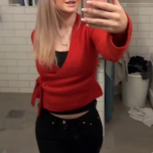 Röd omlottopp - Snygg röd omlottopp med knytning i sidan. Toppen har långa ärmar och en v-ringad design som ger en stilren look. Perfekt för att lägga till en färgklick i garderoben.