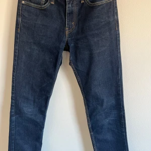 Mörkblå jeans från Levi's - Snygga mörkblå Levi's 511 jeans med klassisk design och orange sömmar. Perfekta för en stilren look. De har en smal passform och är tillverkade i slitstarkt denim.
