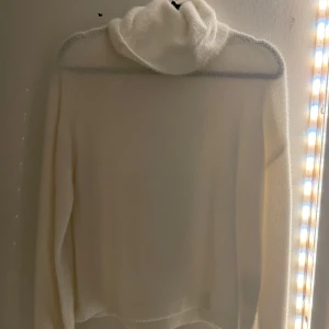 Vit stickad polotröja från Vila - Mysig vit stickad polotröja från Vila. Perfekt för kyliga dagar med sin höga krage och långa ärmar. Tröjan har en mjuk och bekväm känsla, idealisk för att hålla dig varm och stilren. Ett måste i garderoben för vintern! ❄️