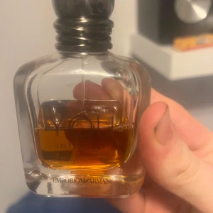 Emporio Armani Parfym - Säljer en elegant parfym från Emporio Armani. Flaskan har en stilren design med en rundad form och en mörk kork. Doften är intensiv och passar perfekt för den som vill ha något unikt och sofistikerat. Perfekt för att ge en lyxig touch till din doftsamling.