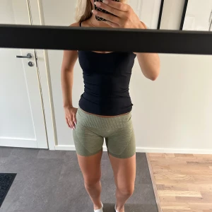 Gröna ribbade träningstights shorts - Snygga gröna shorts i ribbat material, perfekta för träning. De är högmidjade och har en tight passform som sitter skönt på kroppen. Storlek S och är i bra skick.