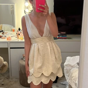 Vit/beige kortklänning med v-ringning - Supersöt kortklänning med djup v-ringning, med fina detaljer! perfekt nu till studenten!!🫶🏻