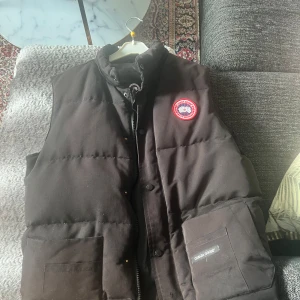  dunväst från Canada Goose - Äkta Canada Goose Freestyle väst i svart. Välanvänd men i fint skick förutom trasig dragkedja (går att laga hos skräddare). Nypris ca 6500 kr. Säljes i befintligt skick, priset är inte hugget i sten vid snabb affär 