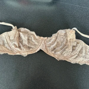 Beige spetsblus från Change, 70dd men skulle säga att den är mer 70b - Supersöt beige spetsblus från Change med tunna axelband och fina rosettdetaljer framtill. Perfelt under vita T-shirts!! Blusen har ett romantiskt spetsmönster och är perfekt för dig som gillar en feminin och elegant stil. Storlek 70DD/32D. Mer 70b