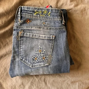 Jeans - jätte fina lågmidjade bootcut jeans,  jätte fina broderade detaljer på baksidan. Dom är tyvärr förstora för mig och därför säljs💖Tyvärr har gylfen gått sönder men finns en extra knapp där, men de märks ändå inte fasten man inte använder den.                                             midjemått: 34,5cm rakt över.                             Innerbenslängd: 74cm