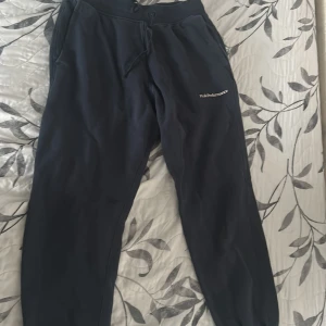 Mörkblå mjukisbyxor från Peak Performance - Säljer ett par mörkblå mjukisbyxor från Peak Performance med dragsko i midjan och fickor på sidorna. Byxorna har en avslappnad passform och är perfekta för chill dagar. Broderad logga på ena benet och resår vid bensluten.