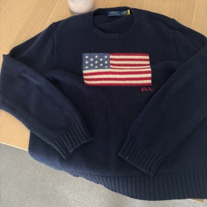Mörkblå stickad tröja Polo Ralph Lauren - Mörkblå stickad tröja från Polo Ralph Lauren med usa flagga på. Köpt för cirka 5500kr, passar runt 180-190cm. Jättebra skick på tröjan, pris ej hugget i sten!