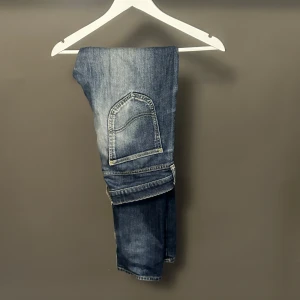 Blå Luke jeans från Lee W30 L32 - Säljer ett par blå Luke jeans från Lee i storlek W30 L32. Jeansen har klassisk femficksdesign, snygga slitningar och raka ben. Tillverkade i jeansmaterial med en cool tvättad look och detaljerade sömmar på fickorna.