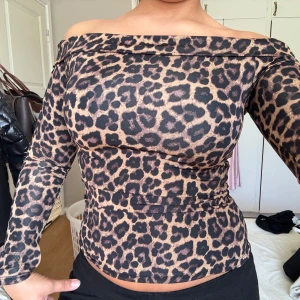 Leopardmönstrad offshoulder topp - Säljer en snygg offshoulder topp med leopardmönster i bruna och svarta toner. Materialet är stretchigt vilket gör att den sitter riktigt snyggt på kroppen.
