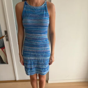 Blå randig kortklänning & Other Stories - Supersnygg blå och vit randig kortklänning från & Other Stories. Tight passform, ärmlös med hög hals och öppen rygg. Perfekt för sommardagar när du vill sticka ut lite extra. Mjuk och skön i materialet, lätt att styla med sneakers eller sandaler. Knappt använd. 