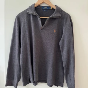  Polo Ralph Lauren halt zip  - Mörkgrå långärmad tröja från Polo Ralph Lauren med klassisk krage och half zip-dragkedja. Broderad logga på bröstet och ribbade muddar. Perfekt för lager-på-lager och chill stil. 1300 isch nypris 