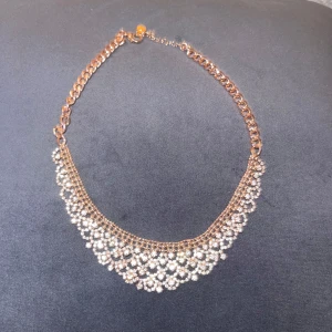 Halsband - Supersnyggt halsband i rose guldton med massor av glittrande stenar i ett tätt, droppformat mönster. Kedjan är chunky och halsbandet ger en lyxig känsla med sina gnistrande detaljer. Perfekt för att lyfta vilken outfit som helst. OANVÄND