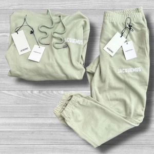 Jacquemus Tracksuit - Snygg ljusgrön tracksuit från Jacquemus med vit logga på bröstet. Tröjan har huva med snörning och en stor magficka. Tillverkad i mjuk bomull, perfekt för chill dagar. Passformen är normal och modellen är klassisk med långa ärmar.