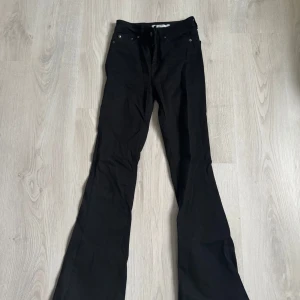 Svarta bootcut jeans från NA-KD - Svarta jeans från NA-KD i bootcut-modell med hög midja. Klassisk femficksdesign, silverfärgade nitar och skön stretchig bomullsblandning. Snygga och tidlösa byxor som ger en clean look.