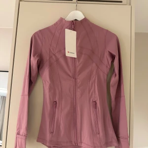 Rosa träningsjacka från Lululemon - Säljer denna oanvända define jacket från lululemon 💗💕storlek 2, funkar bra på mig som har xs