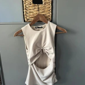 Beige ärmlös topp med cut out från Zara - Beige topp från Zara med cut outs. Endast använd en gång. Storlek S