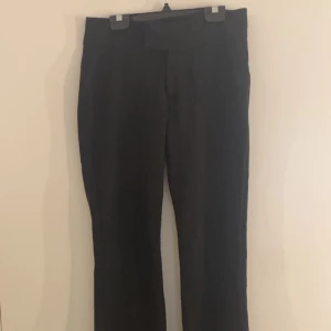Svarta bootcut kostymbyxor - Säljer ett par svarta kostymbyxor med bootcut-snitt och låg midja. Byxorna har en stilren look och är perfekta för dig som gillar klassiska svarta byxor med lite utsvängda ben. Materialet känns mjukt och följsamt. Säljer då de inte längre kommer till användning.💕