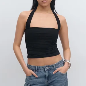 Svart halterneck croppad topp - Snygg svart halterneck topp med croppad passform och breda axelband. Toppen är ärmlös och har en lätt draperad effekt framtill. Perfekt för dig som gillar minimalistisk stil och vill ha en topp som sticker ut med sin unika skärning. Toppen är ny med prislapp kvar🖤