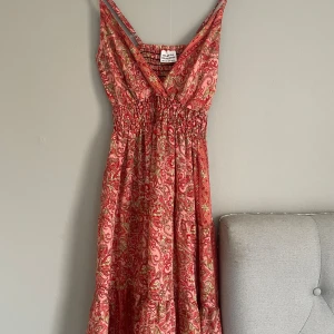 Rosa paisleymönstrad klänning - Supersnygg sommarklänning! . Klänningen har smala axelband, omlott-v-ringning och smockad midja för en bekväm passform. Tillverkad i en mix av silke och polyester, perfekt för sommarens varma dagar.  Köpt i barcelona🙌